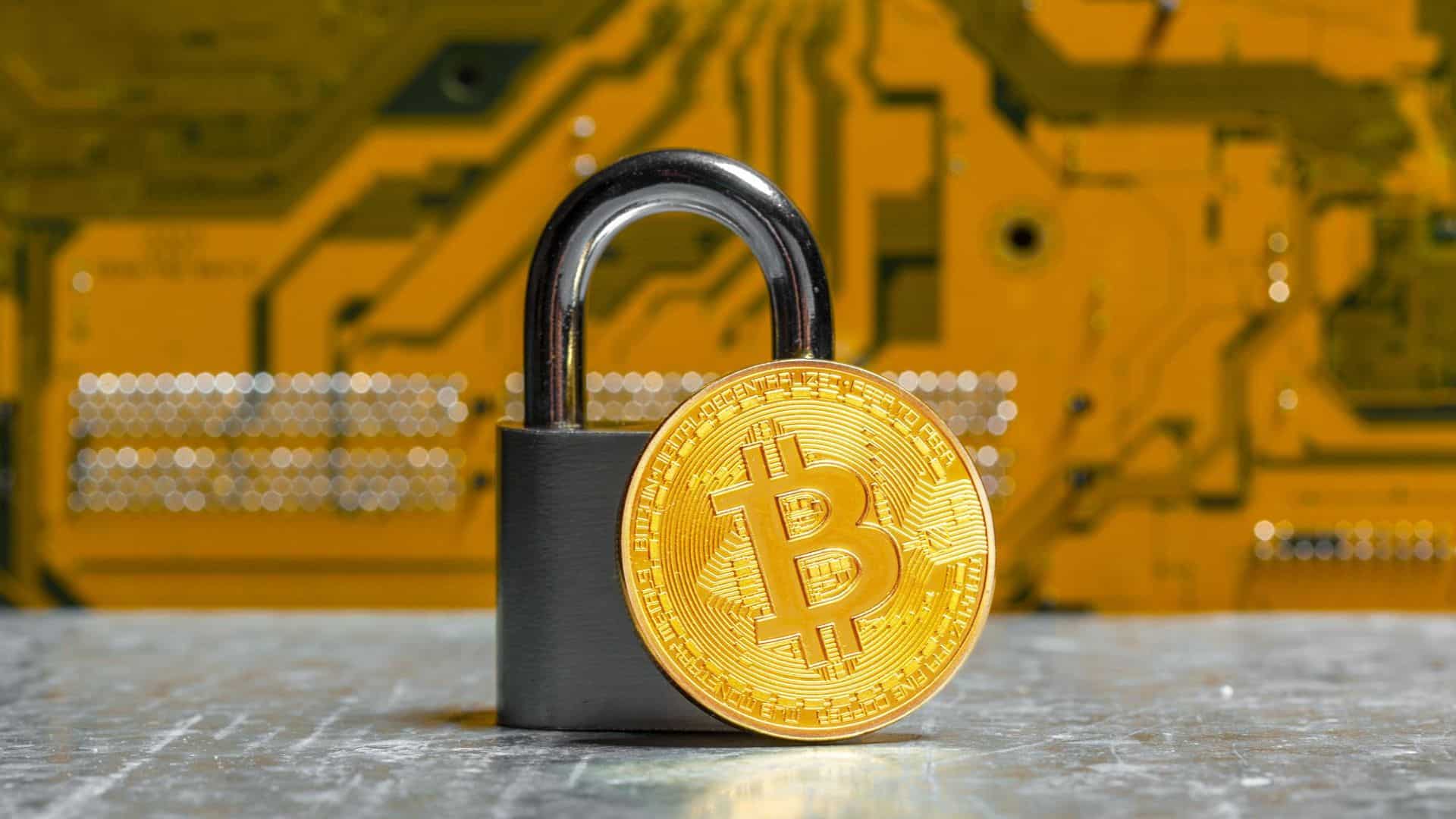 Bitcoin proximo de cadeado com placa de circuito eletronica ao fundo