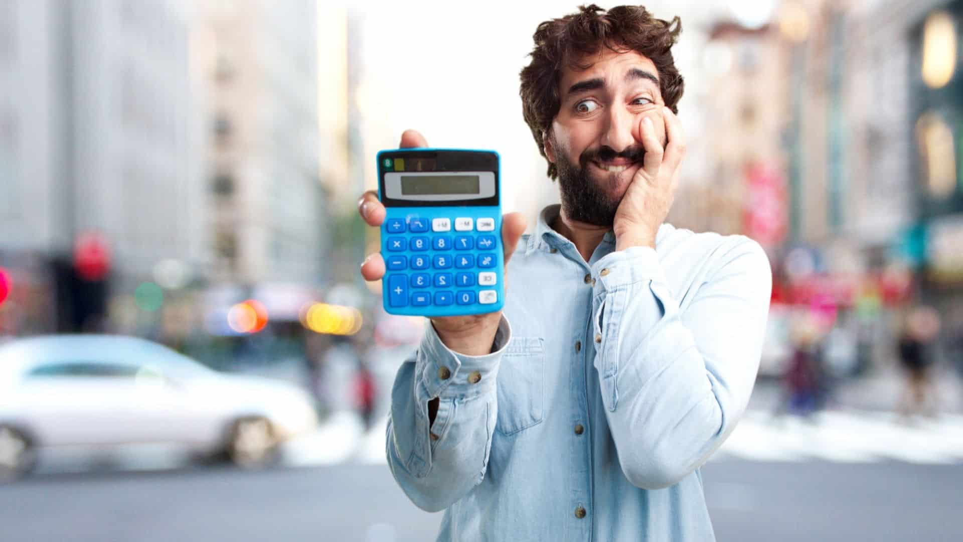 Homem barbado assustado ao segurar calculadora