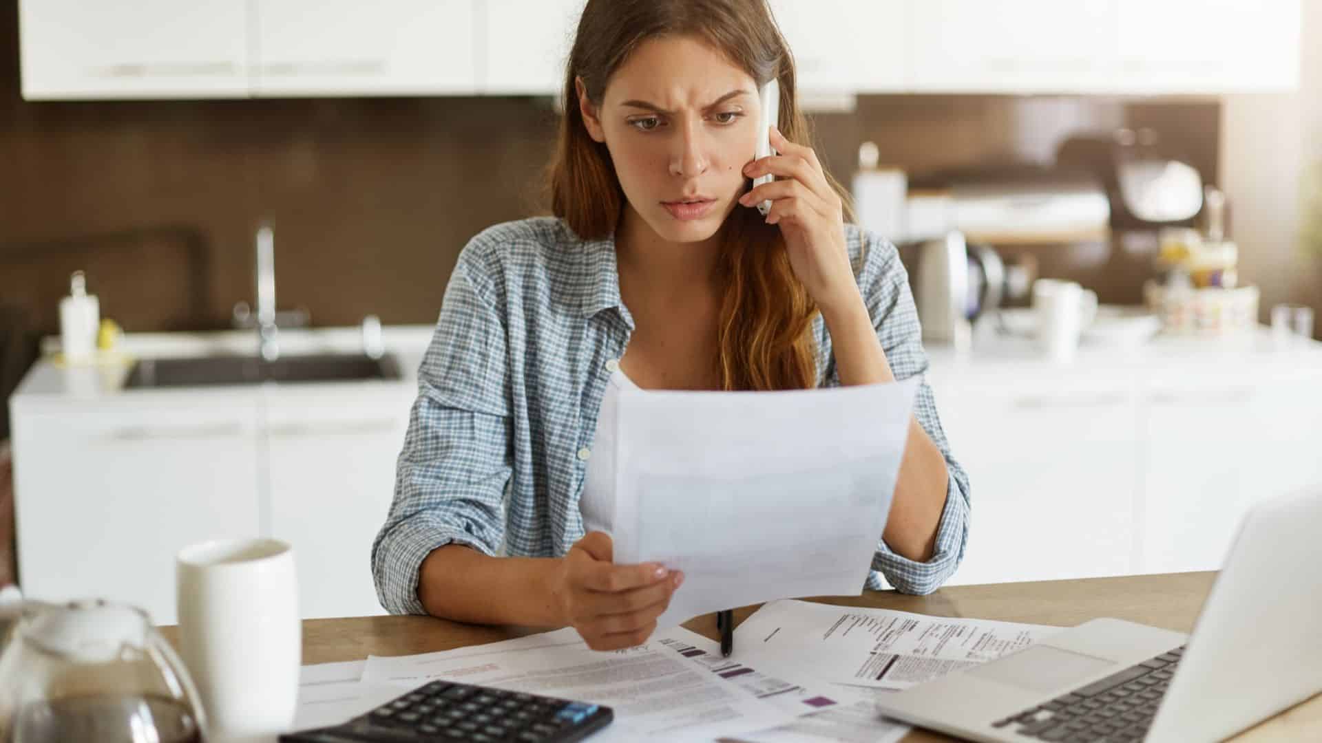 Mulher assustada ao observar papel de imposto