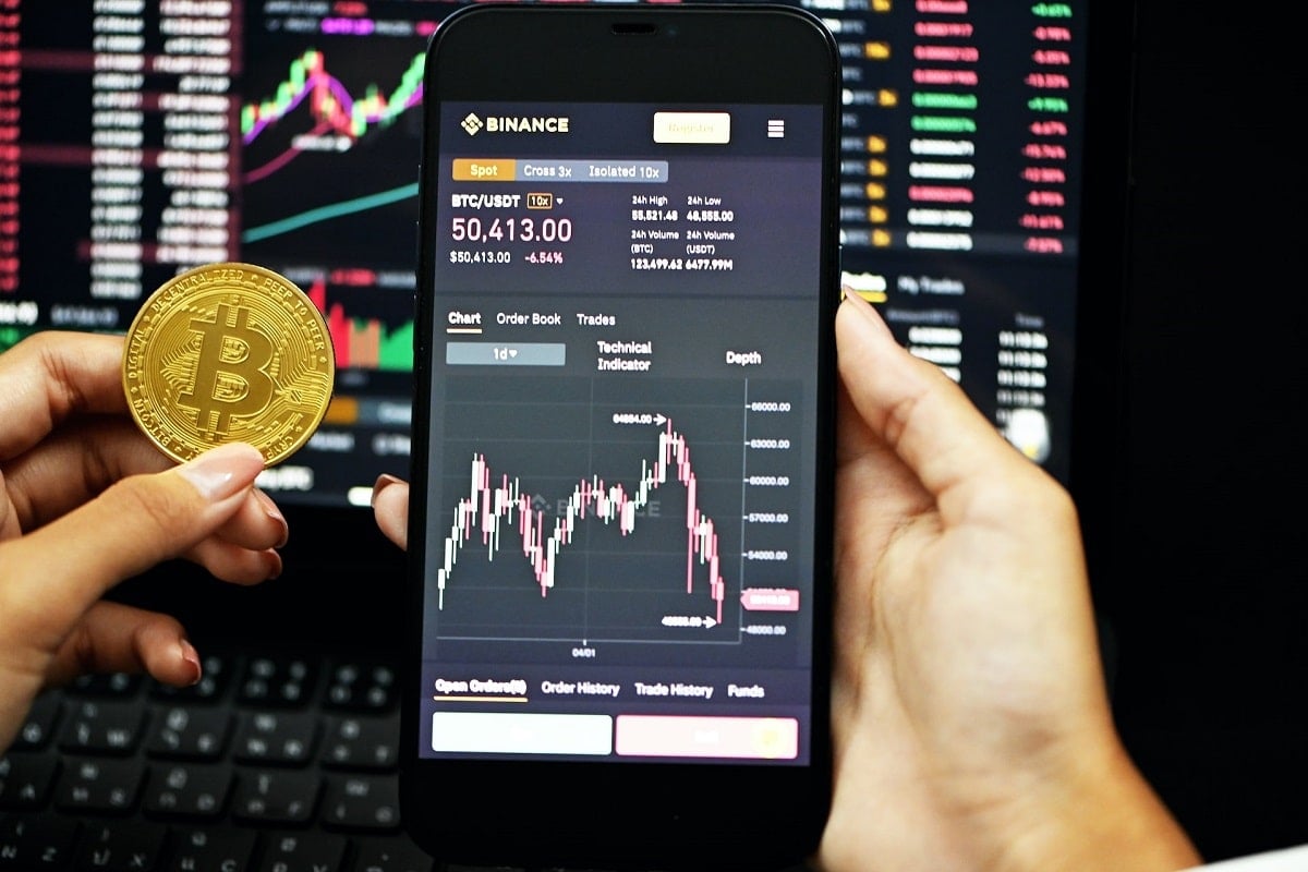 Binance Revela Airdrop Surpreendente: Nova Cripto Dispara 29% em um Dia! 1 Aplicativo e site da Binance ao lado de bitcoin. Foto Kanchanara