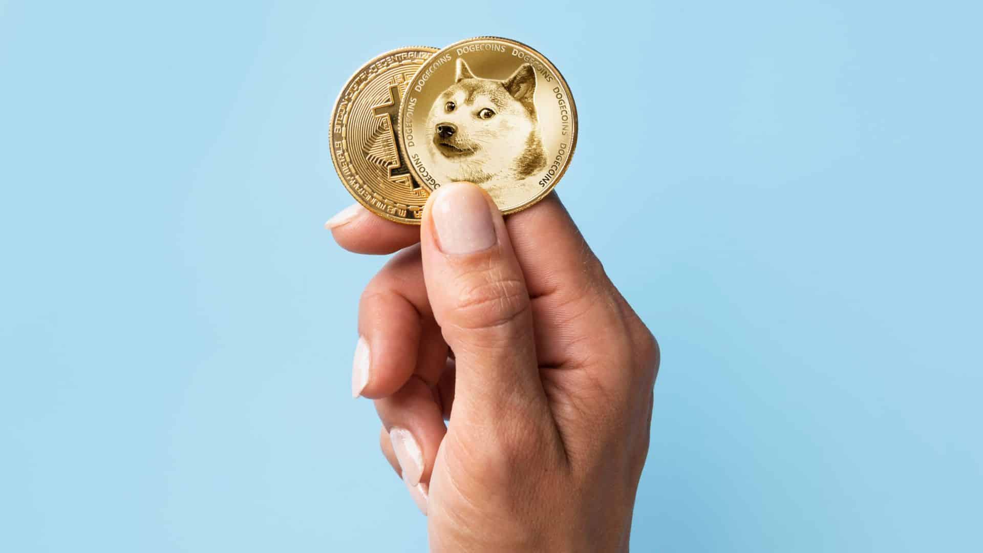 Close em mao segurando Dogecoin e Bitcoin