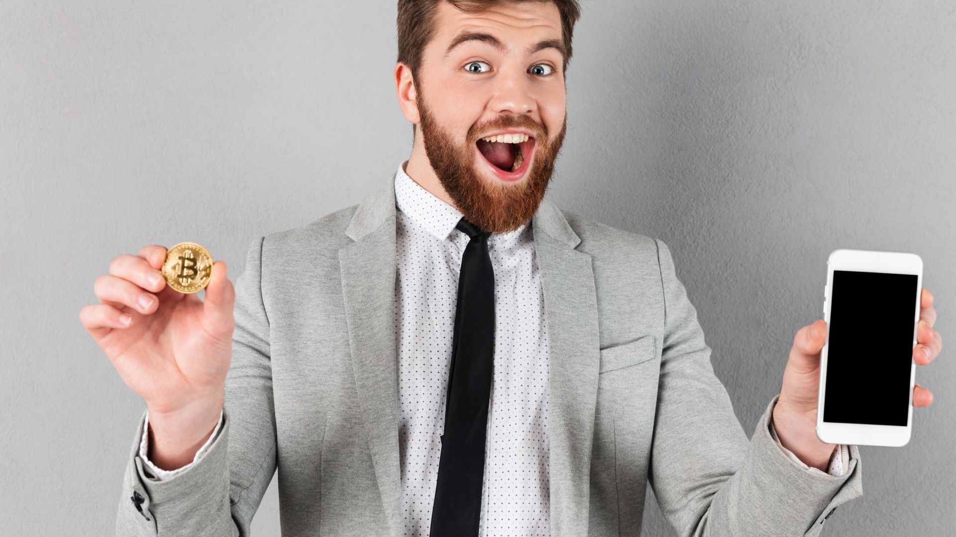 Homem animado com bitcoin e celular