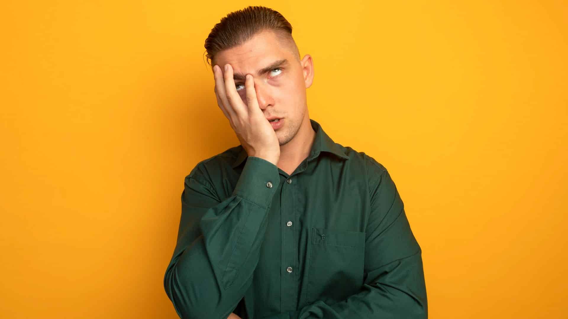 Jovem confuso com mao no rosto olhando para cima