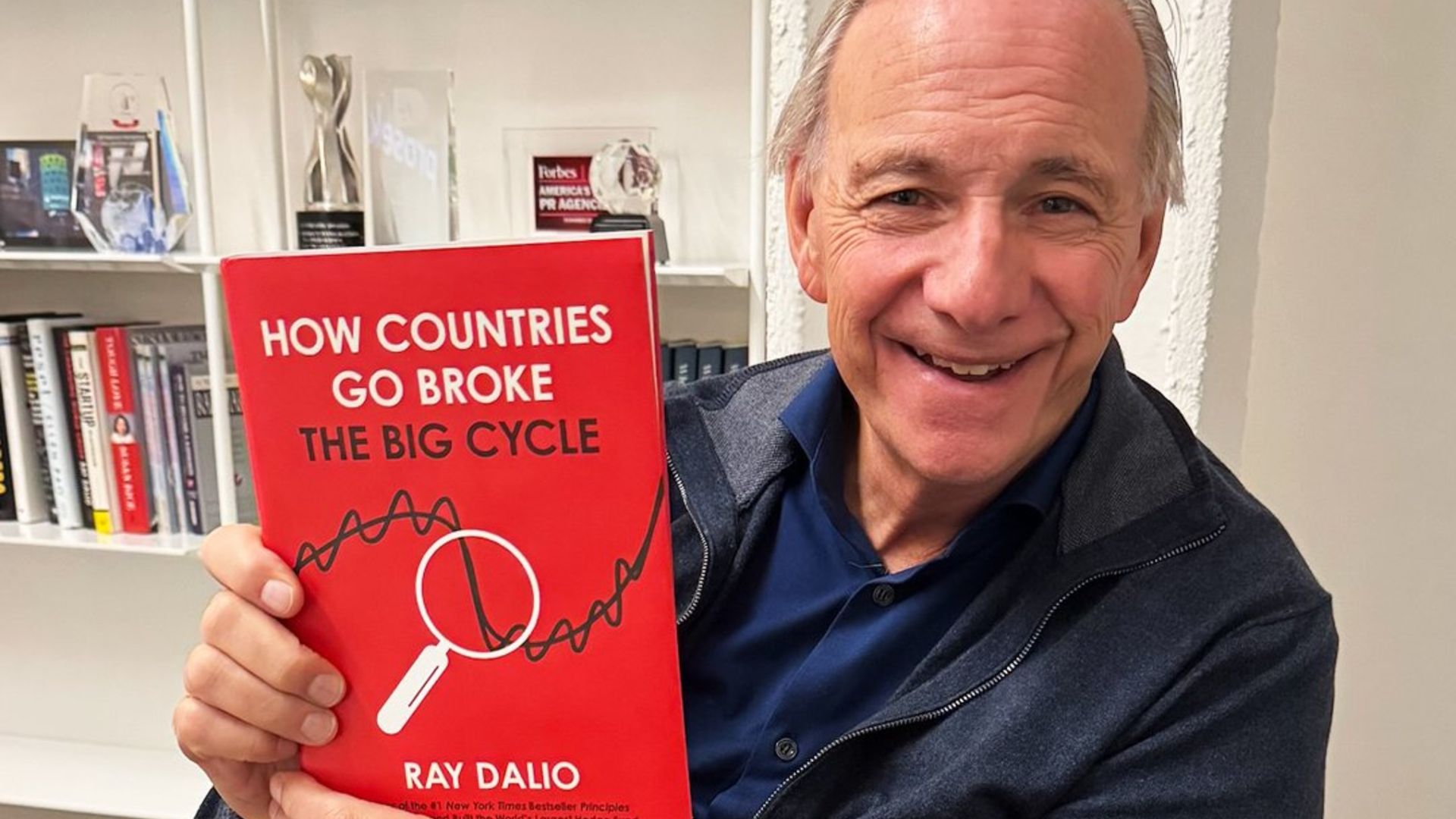 Ray Dalio segurando livro de sua autoria