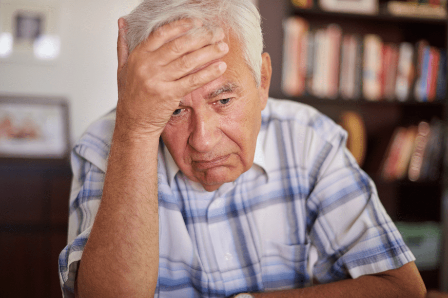 homem senior pensativo na sala de estar