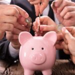 Descubra Quanto Você Pode Acumular Investindo a Isenção de IR de até R$ 5 Mil! 1 Investidores colocando moedas em cofre de porquinho