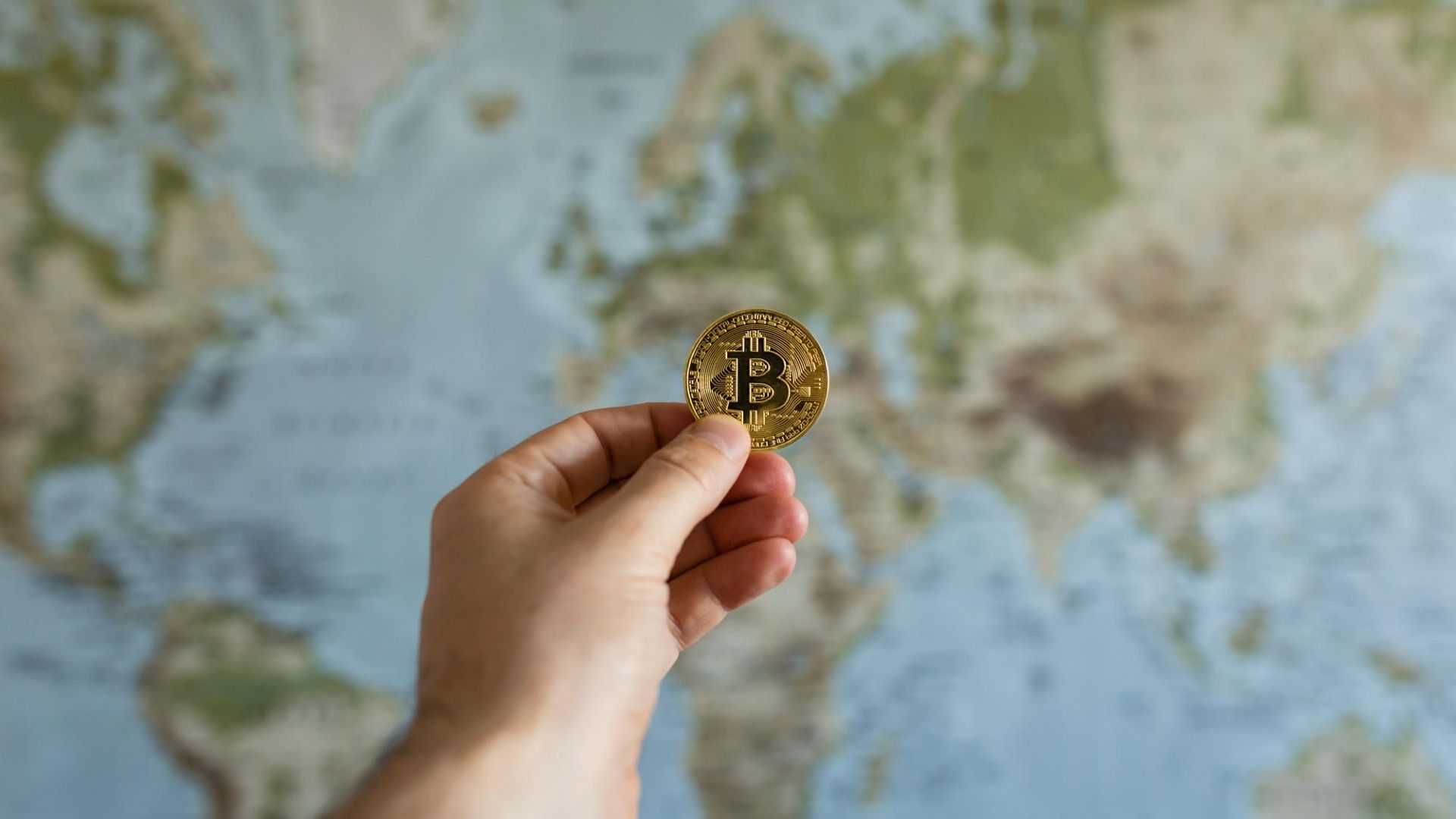 MPF Clama por Ação Global Imediata para Rastrear Criptomoedas! 1 Mao segurando bitcoin na frente de um globo terrestre