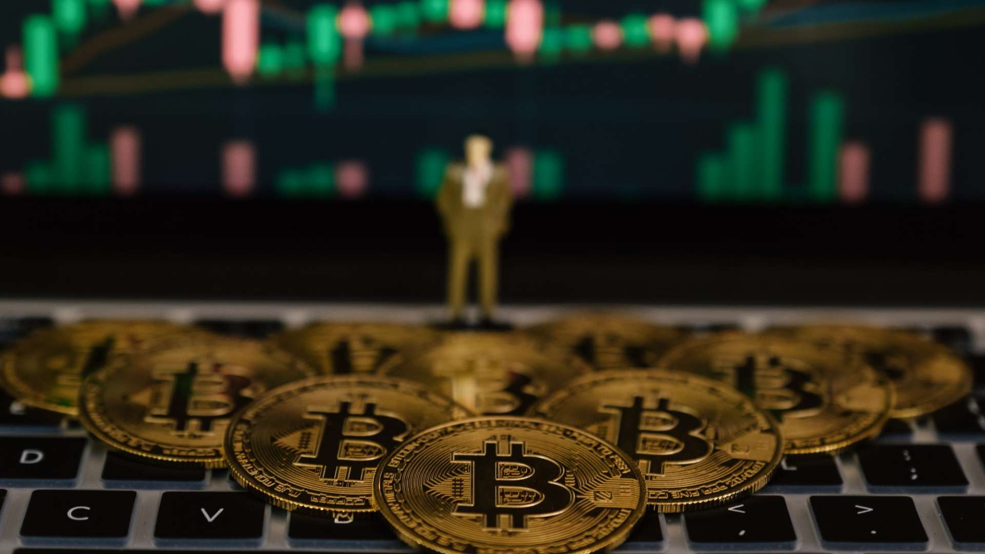 Bitcoins sobre computador com grafico ao fundo