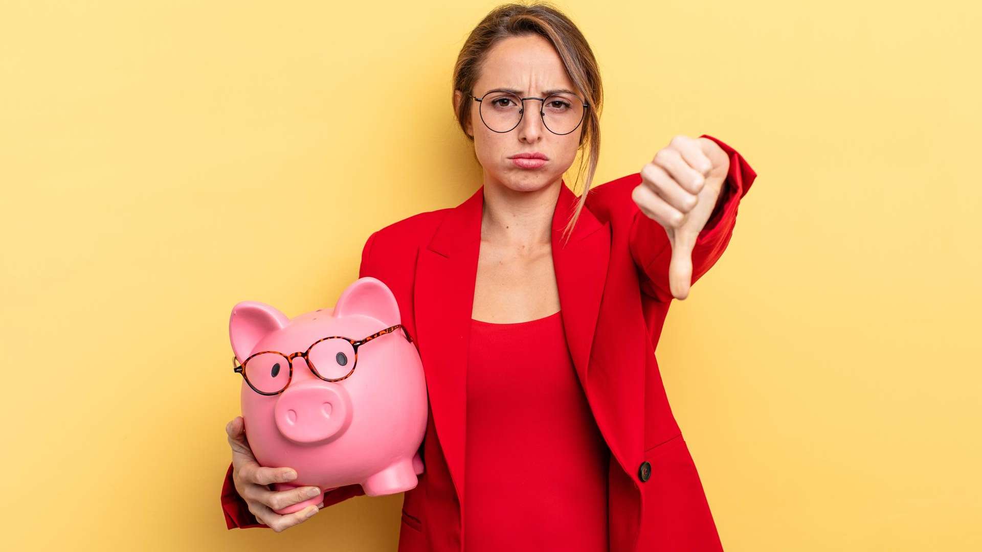 Mulher segurando porquinho de investimentos com sinal de negativo na mao