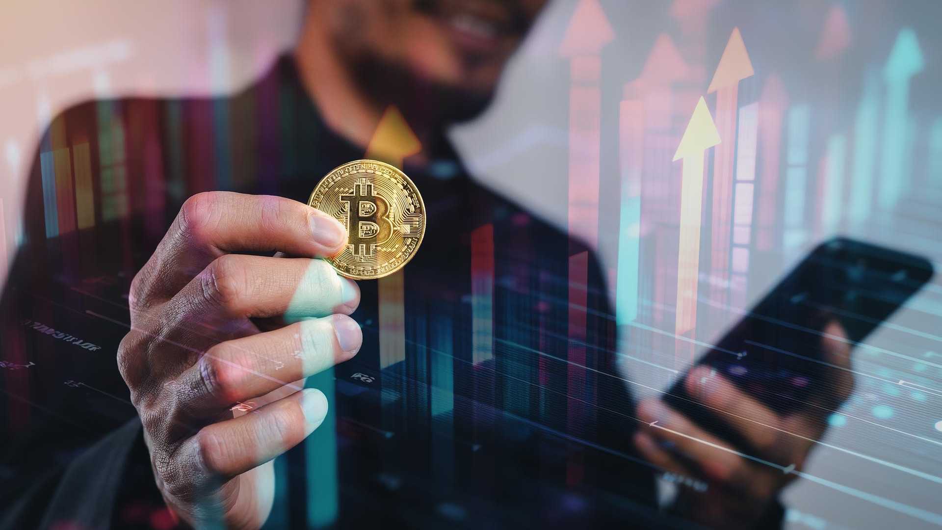 Homem segurando bitcoin com graficos