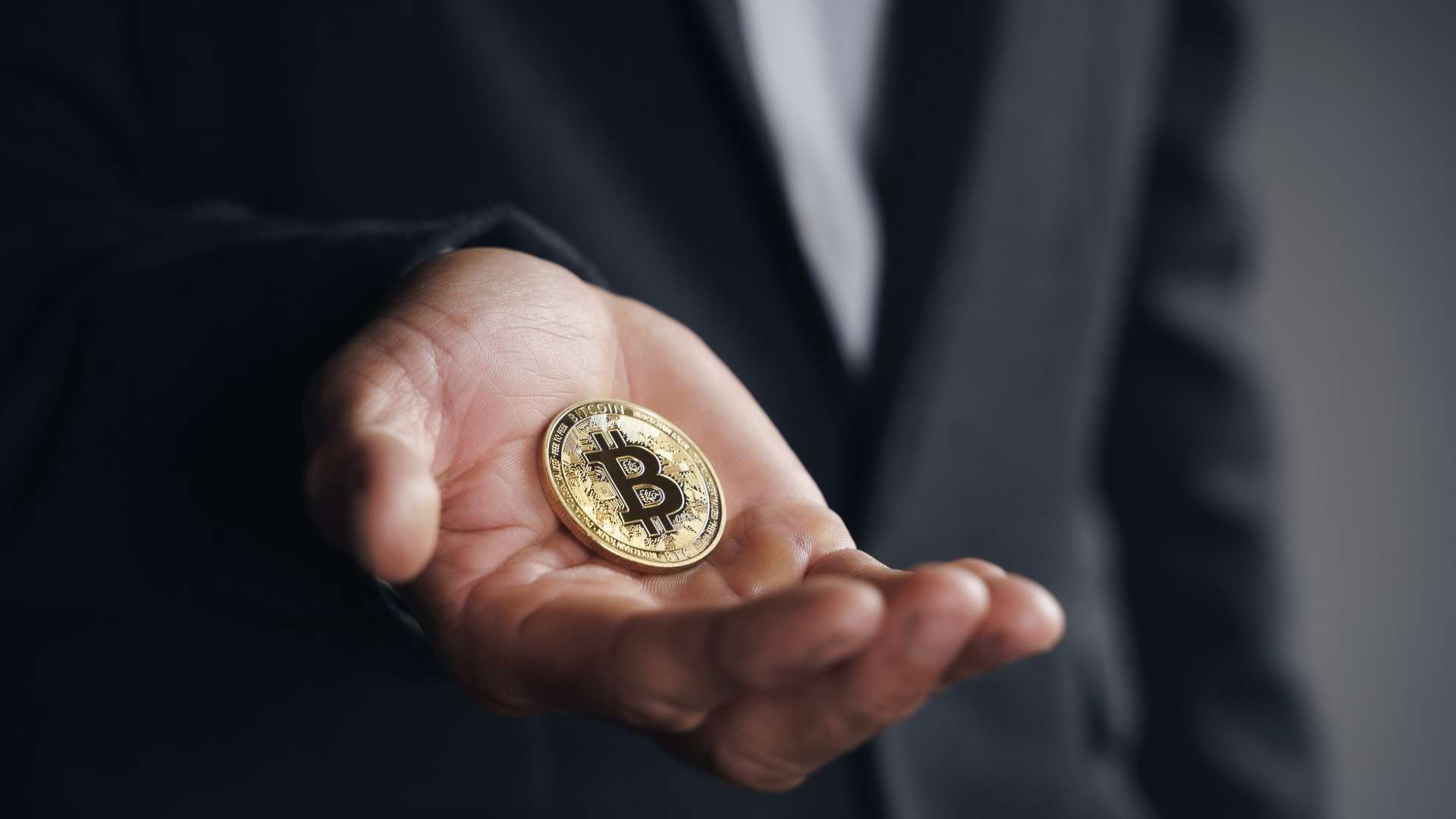 Homem de terno segurando bitcoin em destaque