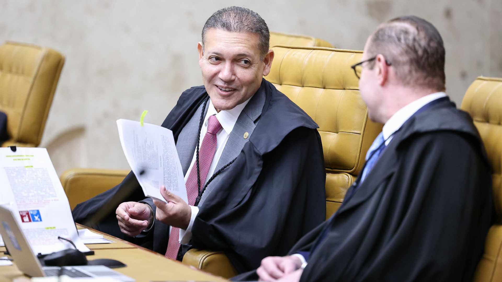 Ministro Nunes Marques segurando papel em sessao do STF