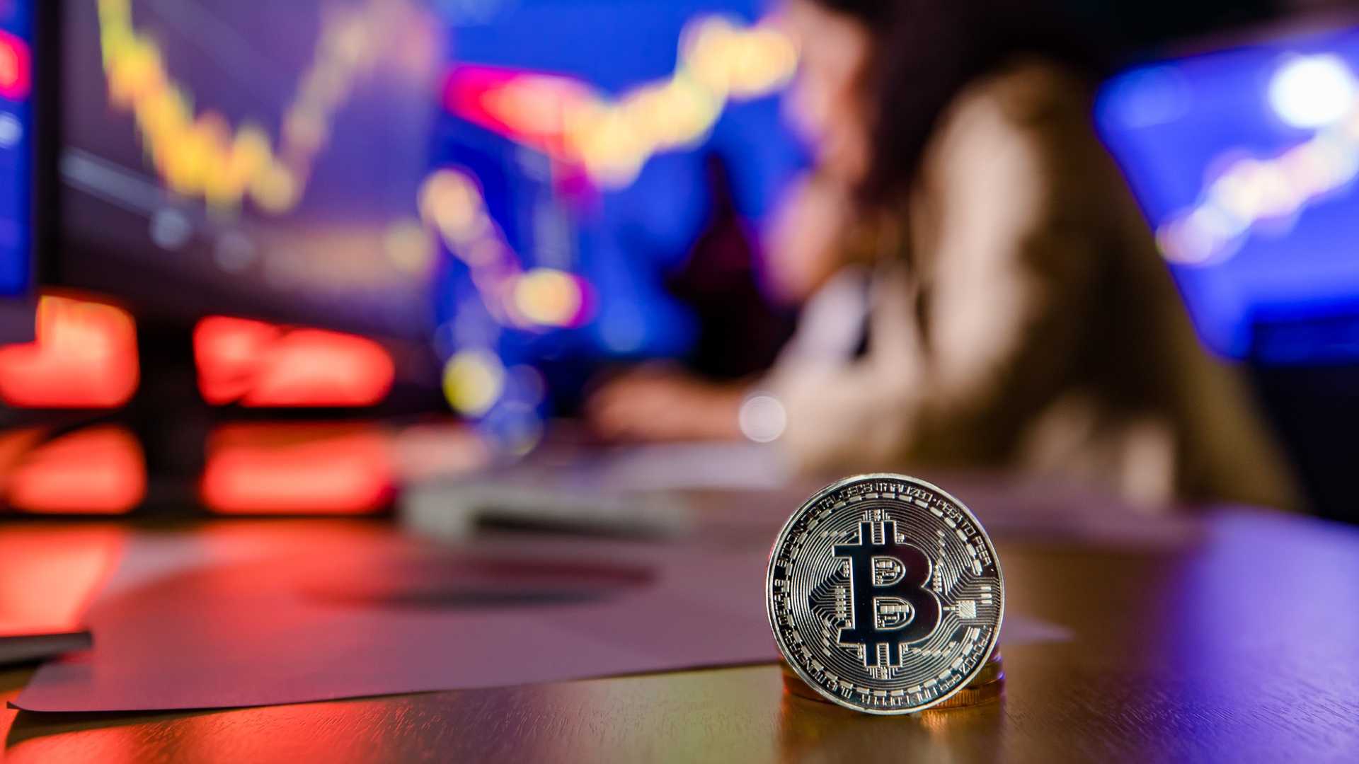 Mulher ao fundo fazendo analise do bitcoin