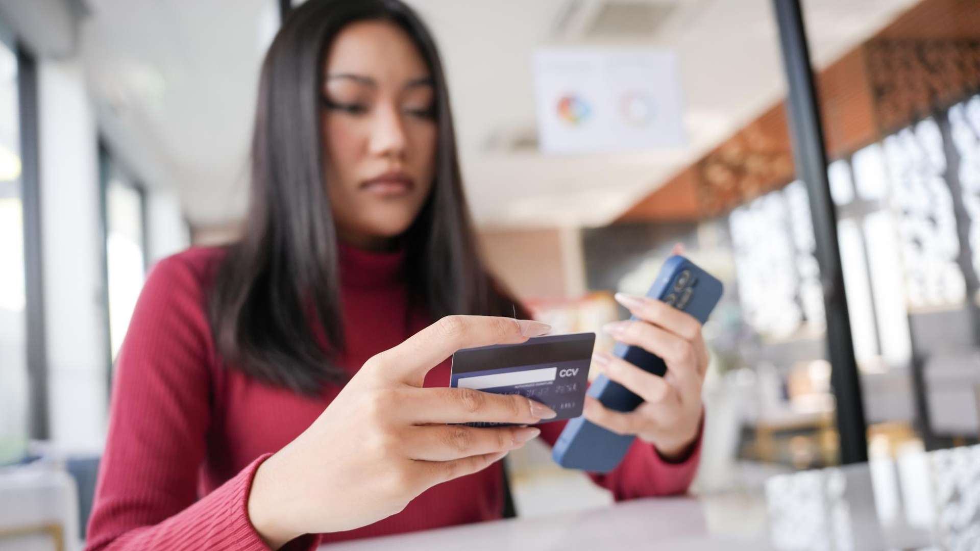 Mulher com cartao de banco e celular na mao