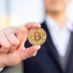 Pessoa de terno segurando bitcoin