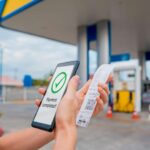 Pessoa pagando em posto de combustivel com aplicativo em celular